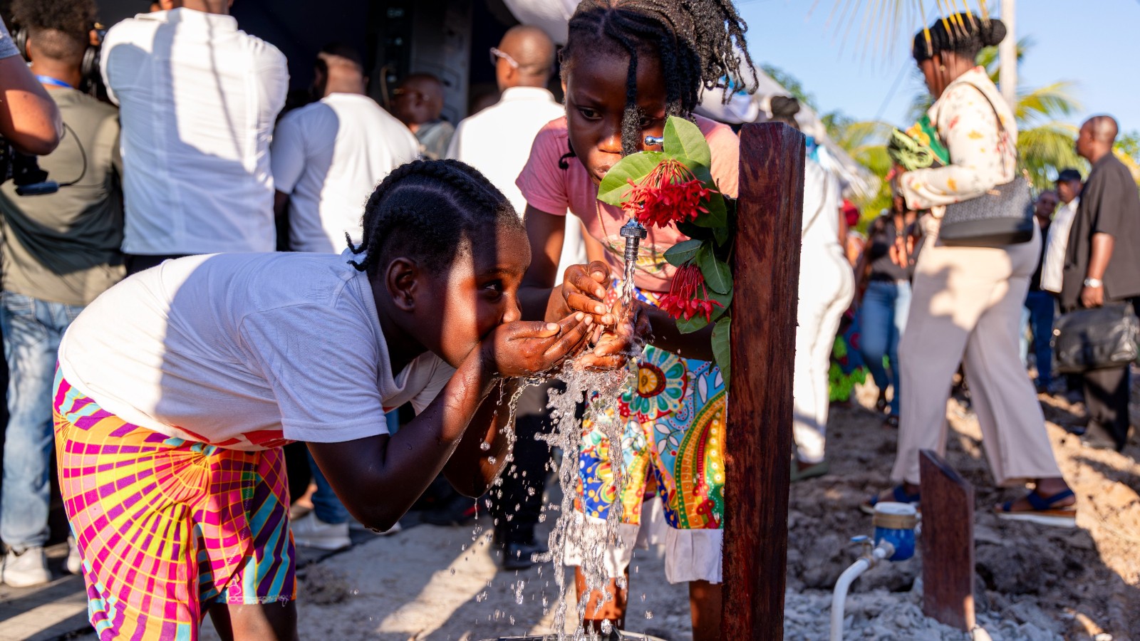 Enkele kinderen maken gelijk gebruik van het water uit de kraan die de president kort daarvoor heeft opengedraaid als teken van de watervoorziening in Sunny Point | Bron: CDS